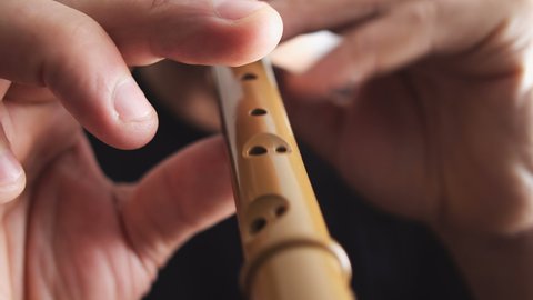 A man playing woodwind wooden flute recorder