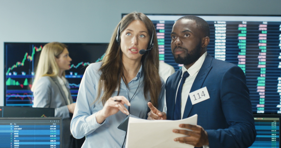 Mixed-races male and female couple of trading co-workers talking and selling or buying stocks with tablet device. African American man and Caucasian woman, traders working in office at exchange market Royalty-Free Stock Footage #1059598814