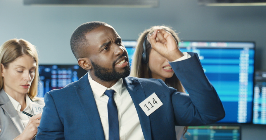 African American young man broker selling or buying on stock market with Caucasian females co-workers. Male trader putting bets and rates at exchange. Mixed-races colleagues of trading screaming. Royalty-Free Stock Footage #1059598859