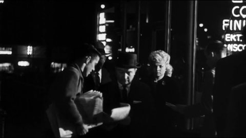 CIRCA 1961 - In this crime movie, men sell newspapers on a city street at night with a headline about a murderer's execution.
