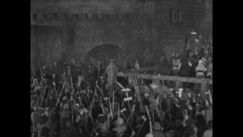 CIRCA 1923 - In this silent movie adaptation of the Hunchback of Notre Dame, Quasimodo looks on in excitement as invaders approach Notre Dame.
