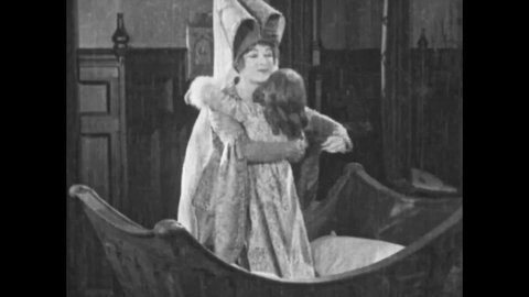 CIRCA 1923 - In this silent movie adaptation of the Hunchback of Notre Dame, an aristocratic woman lovingly puts her young daughter to bed.