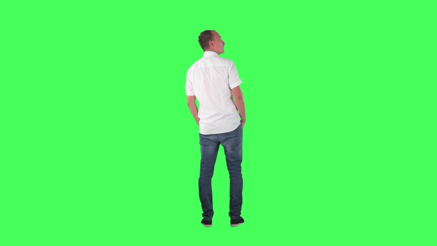Back view of amazed interested young man watching shop window or gallery copy space. Full body on green screen chroma key background.