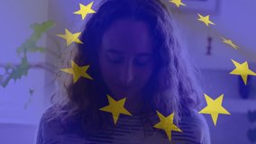 Animation of European Union flag waving on mid section of Caucasian woman self isolating at home, sewing during Covid 19 pandemic. Global coronavirus pandemic concept digitally generated image. - Powered by Shutterstock - Get 15% off with code: PIKWIZARD15