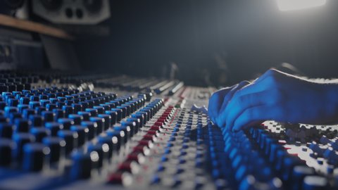 Close up of woman hands producer working at mixing panel in recording production studio. Modern music record studio control desk of digital audio workstation software.