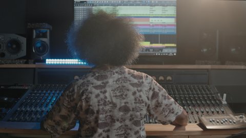 Music production studio. Producer. Latin man working in the recording studio. Brunette male person with afro hair improving his production skills.