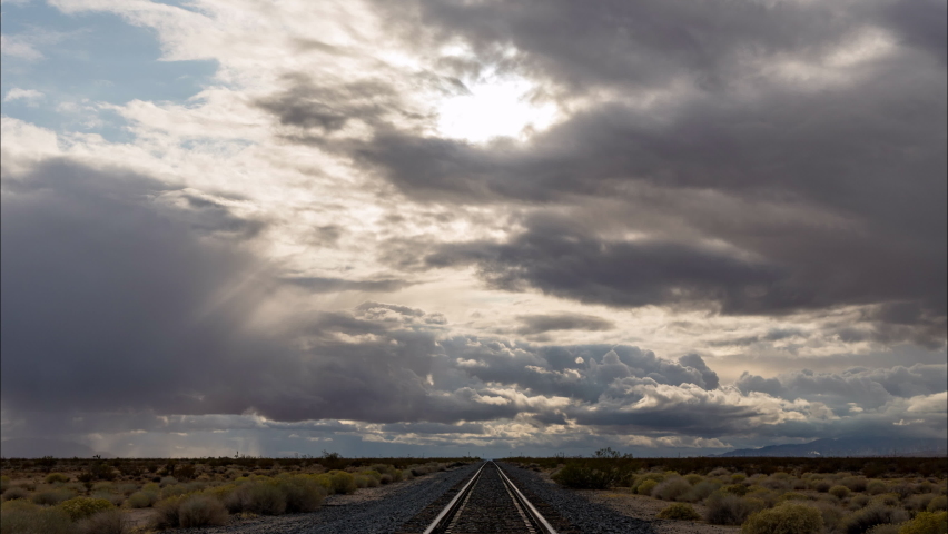 Heavy clouds drifting over train tracks in desert, Time Lapse.