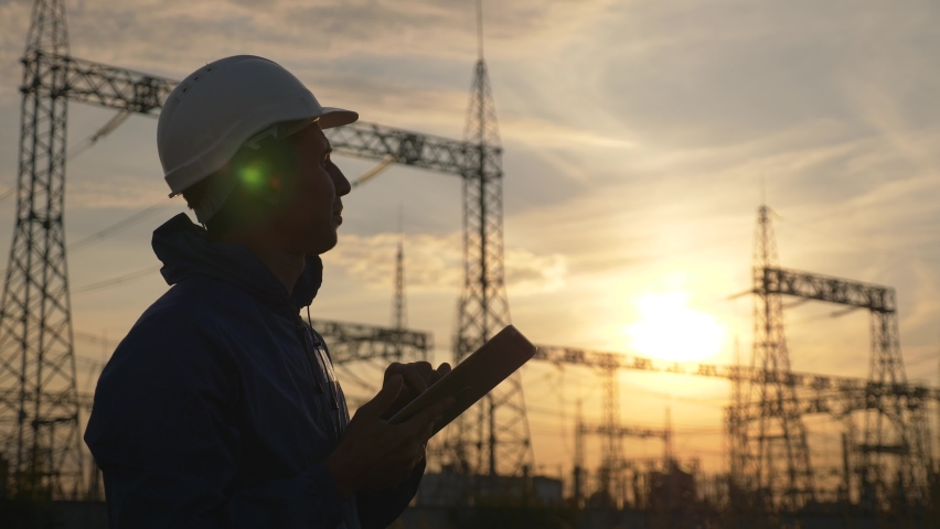 Senior electric engineer working with tablet near electrical lines. Senior electric engineer distributes electrical energy. Businessman electrician working with electrical energy with a tablet Royalty-Free Stock Footage #1059623486