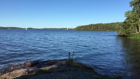 Great view over a part of the large Swedish lake Malar och Malaren. A sunny day in the summer. Cliffs or rocks in the front and a green forest in the background. Järfälla, Stockholm, Sweden.