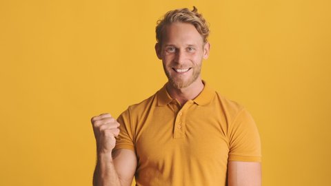 Young attractive blond bearded man happily showing yes gesture on camera over colorful background