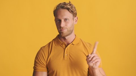 Handsome serious blond bearded man confidently saying no and showing crossed hands on camera over colorful background