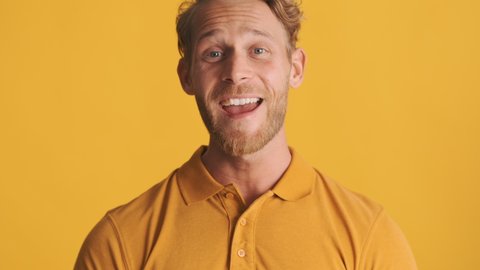 Attractive cheerful blond bearded man happily agreeing on camera over colorful background