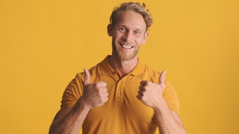 Handsome cheerful blond bearded man happily showing thumbs up on camera over colorful background. Well done expression