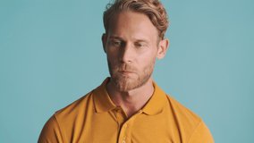 Young handsome blond bearded man thoughtfully posing on camera over colorful background. Thinking expression