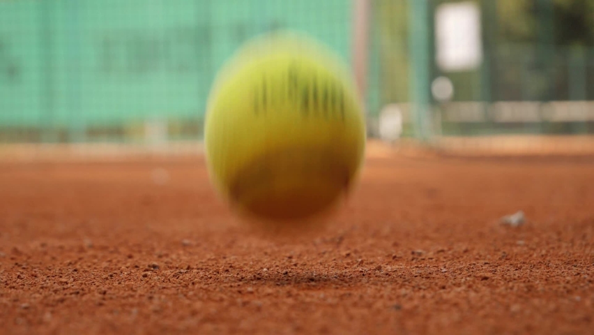 Tennis player bouncing tennis ball on a red tennis court before serving. | Shutterstock HD Video #1059632327