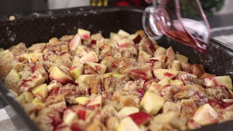 pouring red fruit syrup into a baking sheet with apple pie