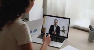 Businesspeople negotiating by videocall, laptop screen view over businesswoman shoulder, employee reporting to boss financial result, business partners discuss sales use video call application concept