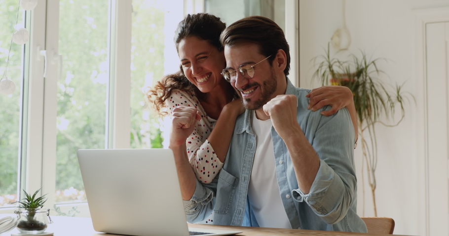 Young family happy couple use laptop read news online received great e-mail scream with joy celebrating unbelievable opportunity. Gamblers lottery monetary win, auction and betting success concept Royalty-Free Stock Footage #1059643817