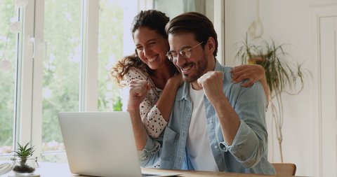 Young family happy couple use laptop read news online received great e-mail scream with joy celebrating unbelievable opportunity. Gamblers lottery monetary win, auction and betting success concept