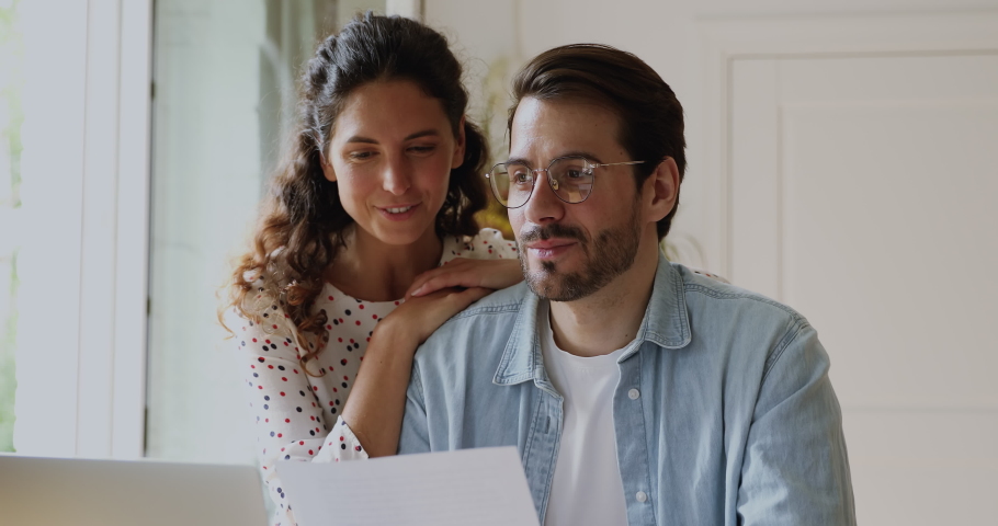 Happy 35s married couple analyzing paperwork planning and discuss budget, reading good news, hold document letter. Family checking paper pay domestic bills, satisfied with money income or taxes refund Royalty-Free Stock Footage #1059643859