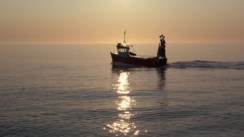 Fishing boat on a calm sea in early morning sunight. Aldeburgh, Suffolk. UK