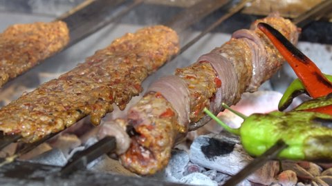 Traditional Turkish cuisine cooked in Adana Kebab grill. Chef cooking meat on barbecue grill for customers. Traditional Turkish shish kebab and vegetables on barbecue fire. Video