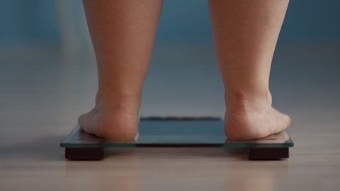 overweight woman is weighed on a scale close up
