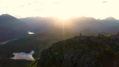 Man Standing On The Summit Of A Mountain At Sunrise