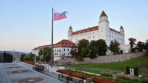 The Bratislava Castle as seen from the precincts of the parliament. A waving Slovak flag in the foreground.