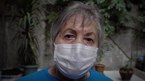 Old woman puts on and takes off two medical masks. color graded and untouched 2 clips in 1.