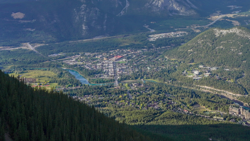 Town of Banff with surrounding mountains. Time-lapse day to dusk in summer time season. View from Sulphur Mountain summit observation deck. Alberta, Canada. Near to far zoom out 4K UHD.