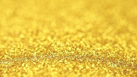 Pile of shimmering small round gold glitter abstract background in close-up. Pouring a surface of glittering sparkling gold glitter. New year and Christmas celebration abstract festive background.