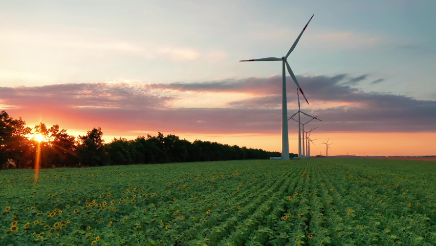 Aerial view of wind turbines standing in sunset. Aerial View of a Farm With Wind Turbines. Generating Clean Renewable Energy. bright orange sunset wind park drone. Alternative energy  Royalty-Free Stock Footage #1059656711
