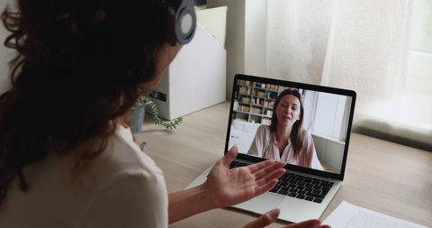 Women chatting by video conference call, laptop screen view over female shoulder. Convenient modern technology usage, personal or business communication remotely. Video call event interaction concept