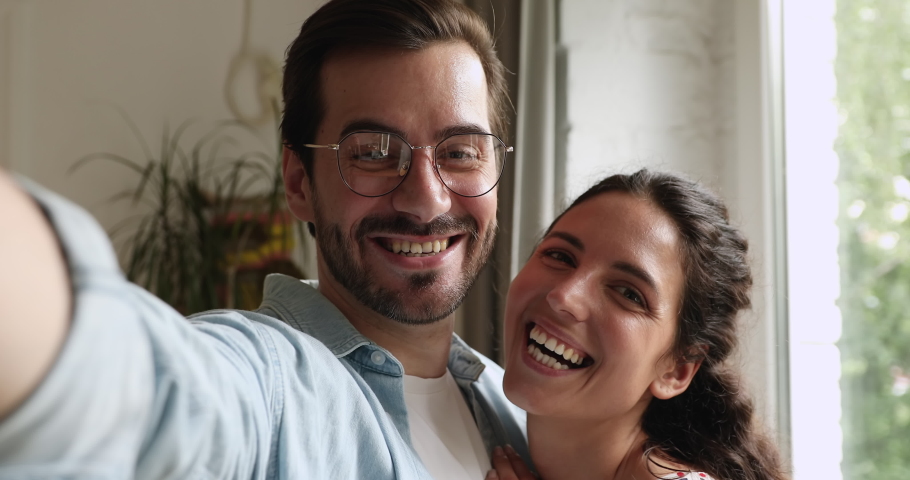 Close up couple laughing feels overjoyed look at camera webcam view. Husband hold cellphone hug wife happy vloggers family record video. Modern tech, romantic relations people in love portrait concept Royalty-Free Stock Footage #1059665726