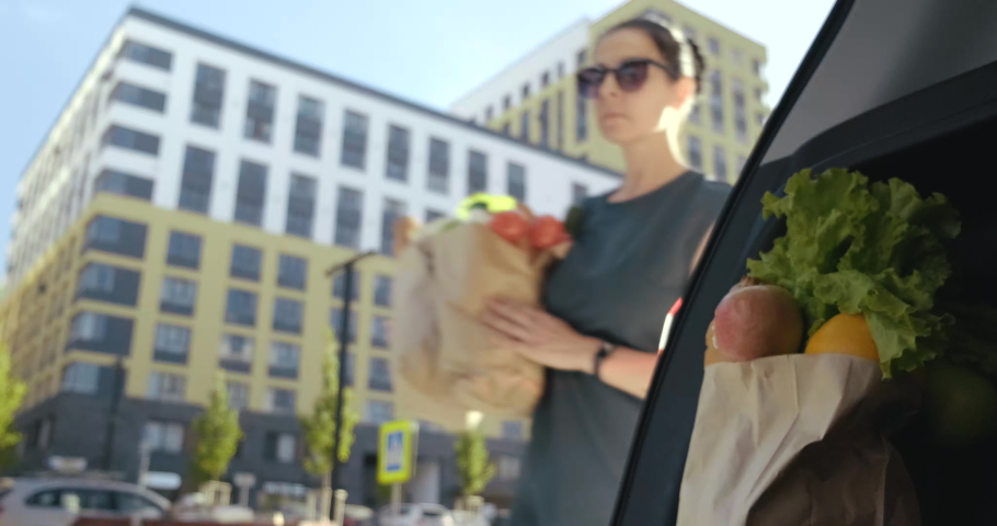 Woman Puts Paper Bags With Groceries For Week In Open Trunk Of Car. Buyer. Resident of Big City. Bought Food at Supermarket. View from Car Trunk. Woman in Sunglasses. Summer. City Street. Closes Trunk | Shutterstock HD Video #1059671150