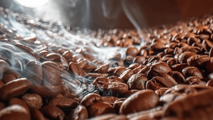 Close up of seeds of coffee. Fragrant coffee beans are roasted smoke comes from coffee beans.