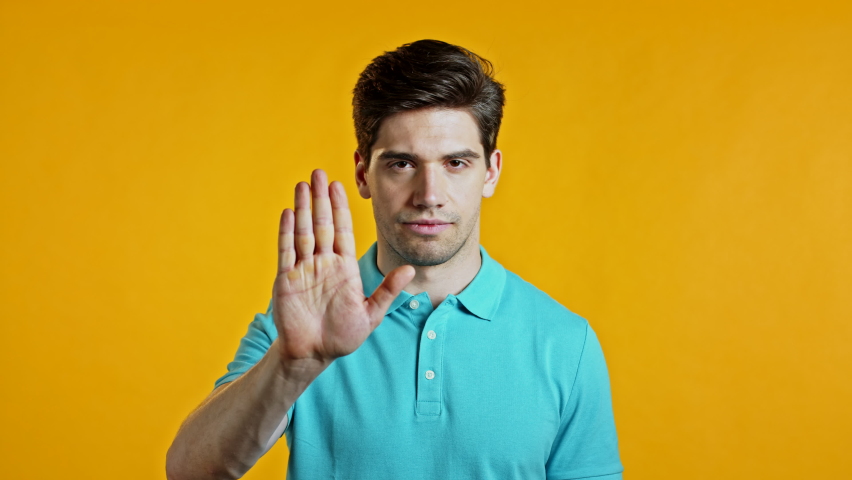 Man disapproving with NO hand sign gesture. Denying, rejecting, disagree, portrait of guy or student on yellow background | Shutterstock HD Video #1059686243