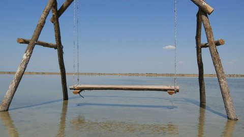 A lonely Wooden swing on the water is picturesquely located on a salt lake, recreation relax concept.