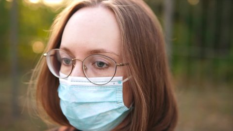 Close up portrait of a woman in fogging misty glasses in a medical mask during a COVID-19 pandemic. Gimbal shot.