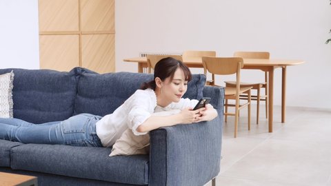 Asian woman using the smart phone on the sofa