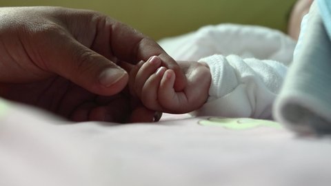 New born baby hand holding father hand during baby sleeping. newborn baby and dad hands. father taking care of her son kid happy family dream of health