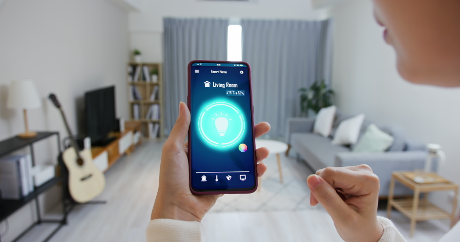 Asian young woman is using smart home app and touch screen to turn on the light by mobile phone | Shutterstock HD Video #1059696950