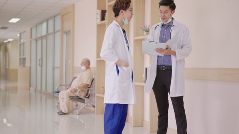 Young asian doctor walk talk and discuss together feeling relax in private ward with concept morning round ward at hallway corridor hospital. Routine health care work at clinic.
