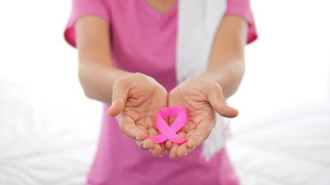 Close up of Hand holding pink ribbon to camera. World breast cancer day concept. Breast cancer symbol.