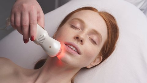 Happy woman receives a hardware phonophoresis procedure from a cosmetologist in a Spa salon.