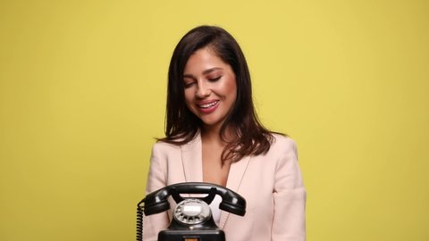 happy beautiful businesswoman talking on the phone, pointing at the camera, gesturing a call me sign and being excited on yellow background