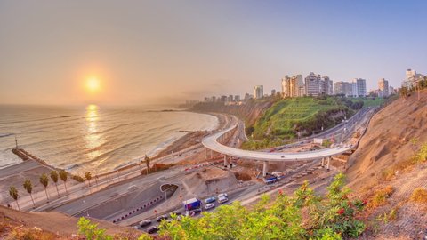 Aerial sunset view of Lima's Coastline in the neighborhood of Miraflores timelapse with orange light, Lima, Peru. Road traffic with junction and beach with ocean from Husares De Junin waterfront