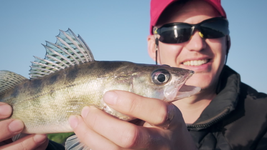 Happy angler with tiny Zander fish