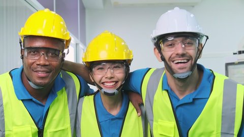 Close up portrait team of young multiethnic group male and female technician staff wearing a protective helmet. Happy teamwork laugh smile posing at camera smiling. Slow motion.